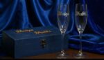 Personalized wine glasses with real silver name detailing placed in front of a custom wooden gift box with matching names